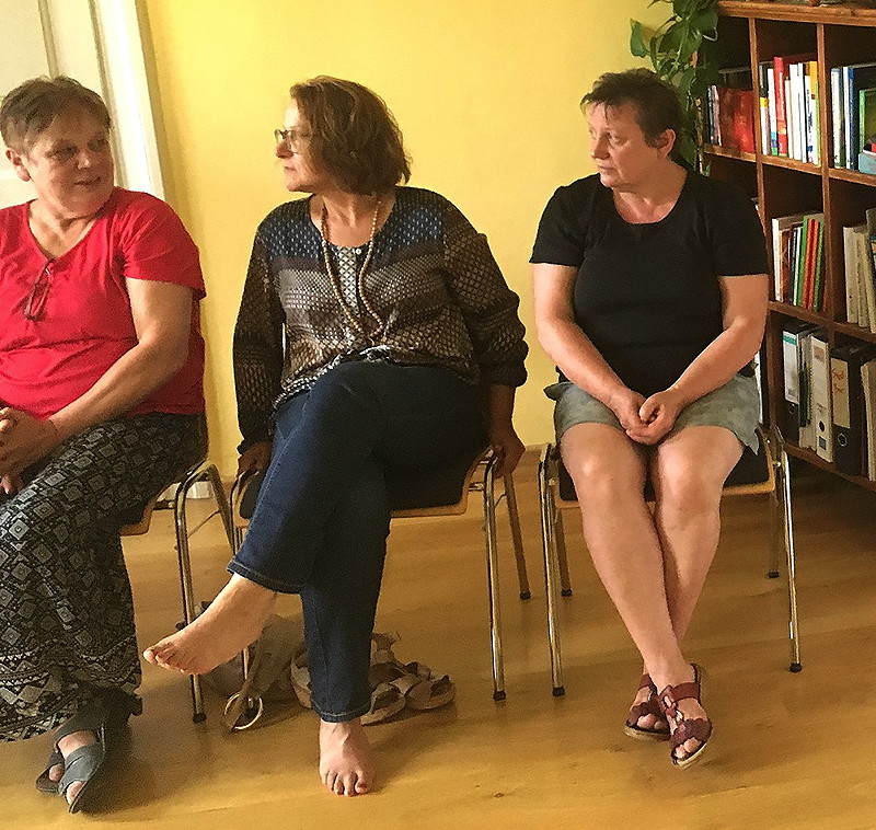 Drei Frauen sitzen auf Stühlen und kommunizieren miteinander